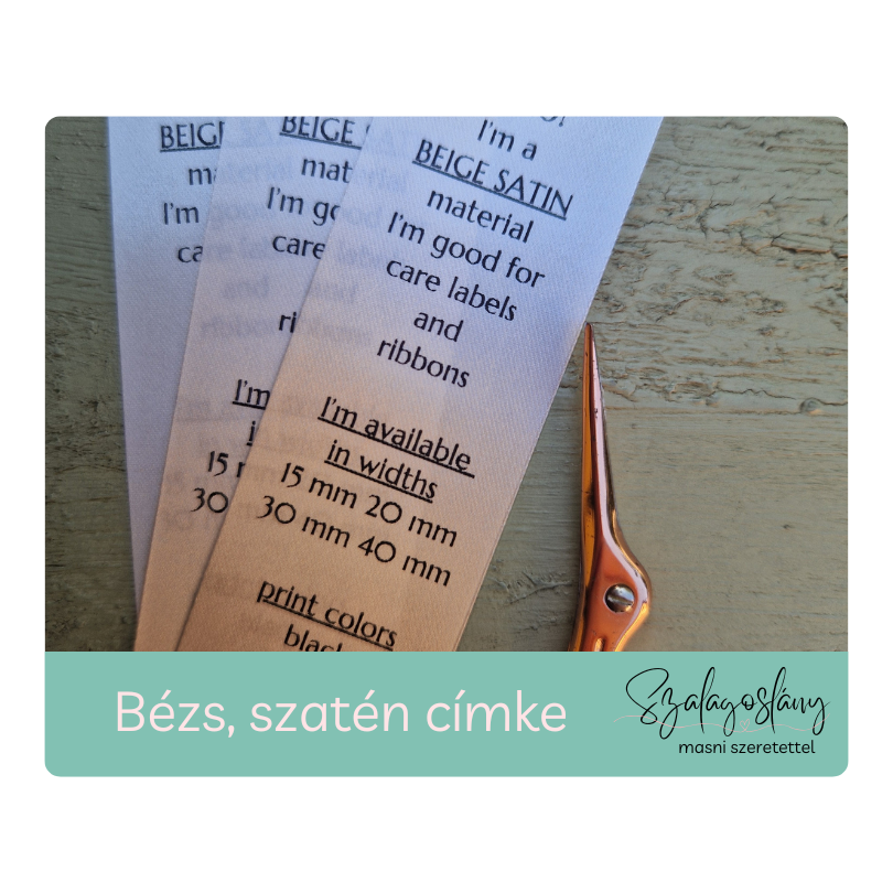 Bézs szatén nyomott, bevarrható címke. Logóval, anyagösszetétellel, kezelési utasítással nyomtatva. Szalagoslány, Lévay Nóra